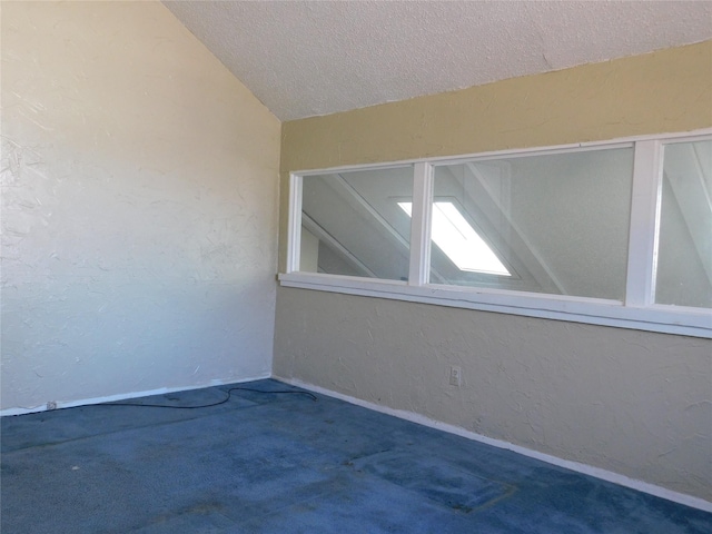 spare room featuring lofted ceiling, a textured wall, and carpet flooring