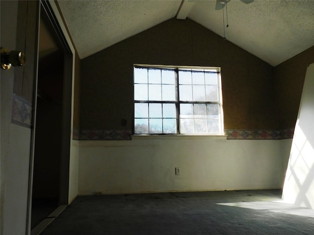 carpeted empty room with ceiling fan and vaulted ceiling