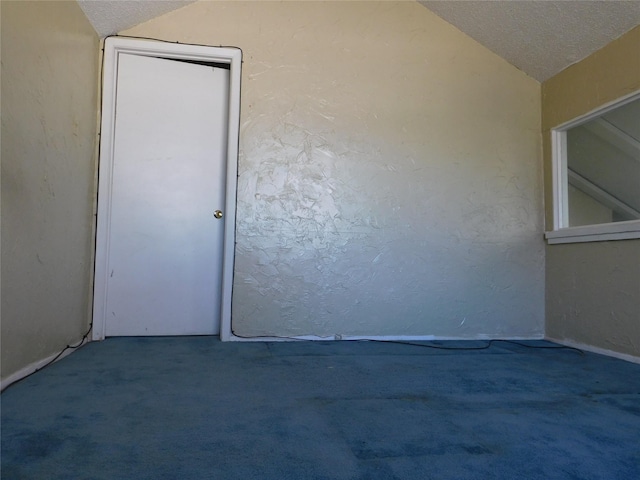 unfurnished room featuring a textured ceiling, vaulted ceiling, carpet flooring, and a textured wall