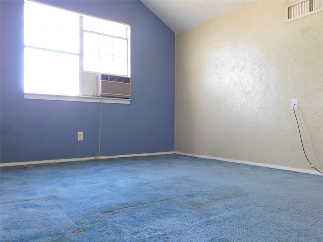 empty room with visible vents, a textured wall, lofted ceiling, carpet, and cooling unit