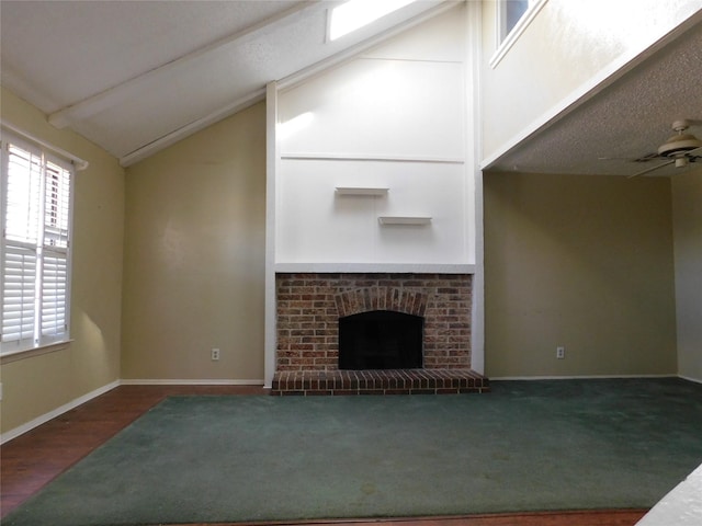 unfurnished living room with vaulted ceiling, a brick fireplace, wood finished floors, and baseboards