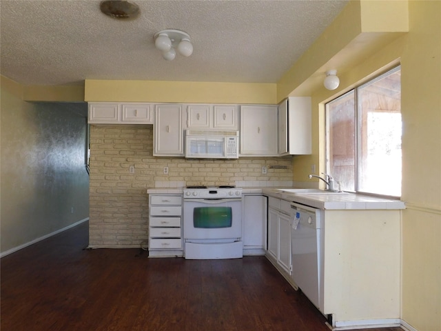 kitchen with tile countertops, white appliances, white cabinetry, and a sink