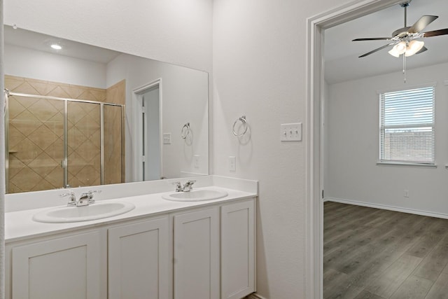 bathroom featuring double vanity, wood finished floors, a stall shower, and a sink