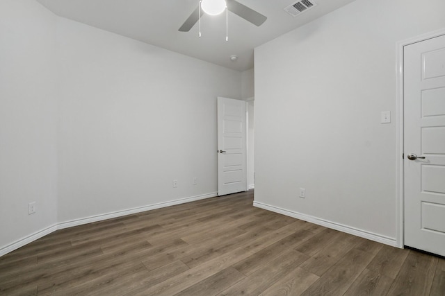 spare room featuring a ceiling fan, wood finished floors, visible vents, and baseboards