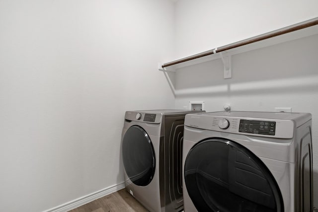 clothes washing area with washer and dryer, laundry area, baseboards, and light wood finished floors