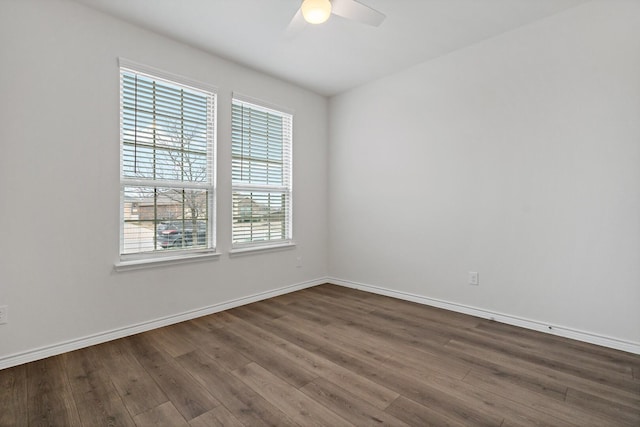 spare room featuring dark wood-style floors, a ceiling fan, and baseboards