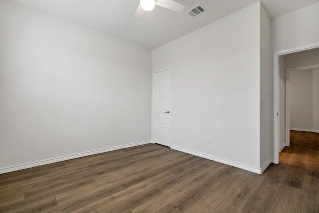 spare room featuring dark wood-style floors, a ceiling fan, visible vents, and baseboards