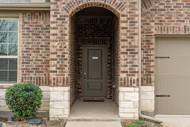 property entrance featuring brick siding and an attached garage