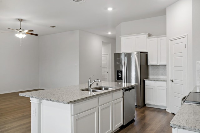 kitchen featuring dark wood-style floors, stainless steel appliances, decorative backsplash, white cabinets, and a sink