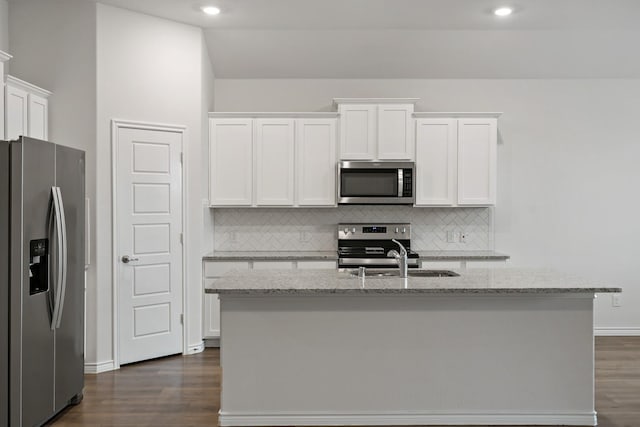 kitchen with dark wood-style floors, appliances with stainless steel finishes, light stone counters, and white cabinets