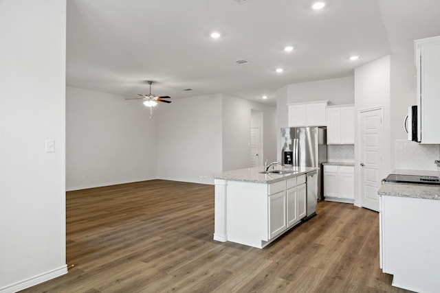 kitchen featuring a center island with sink, tasteful backsplash, white cabinetry, wood finished floors, and range