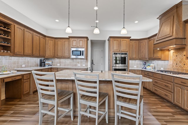 kitchen with dark wood-type flooring, a kitchen island with sink, custom exhaust hood, stainless steel appliances, and backsplash