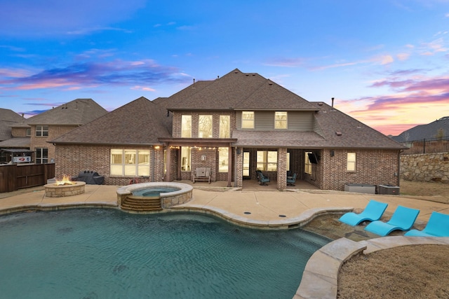 pool at dusk featuring a fire pit, a patio area, fence, and a pool with connected hot tub