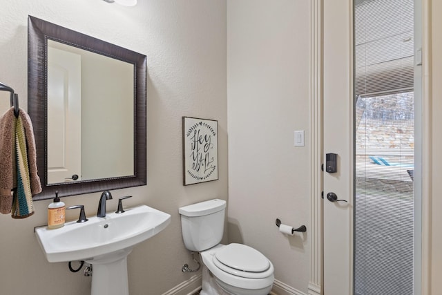 bathroom featuring toilet, baseboards, and a sink