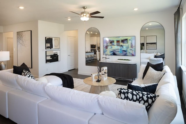 living room featuring arched walkways, baseboards, dark wood-style floors, ceiling fan, and recessed lighting