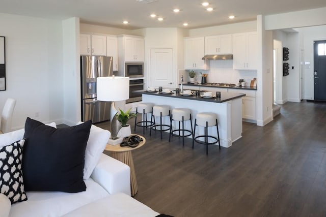 kitchen with a breakfast bar, dark countertops, decorative backsplash, appliances with stainless steel finishes, and white cabinets