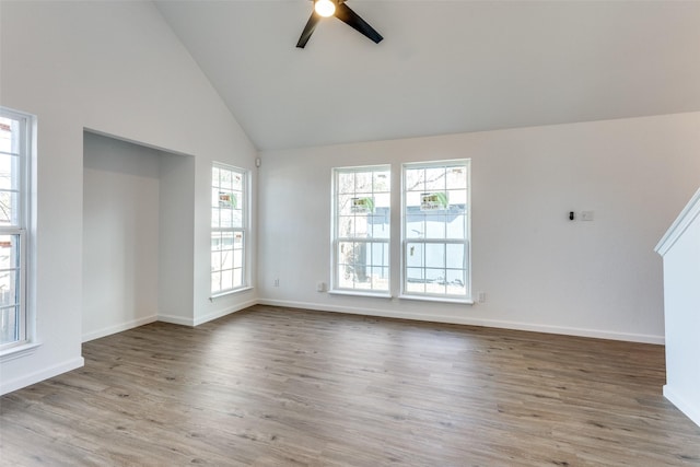 unfurnished living room with high vaulted ceiling, wood finished floors, a ceiling fan, and baseboards