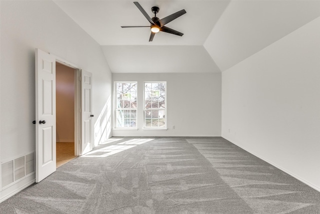 carpeted spare room featuring visible vents, vaulted ceiling, baseboards, and ceiling fan