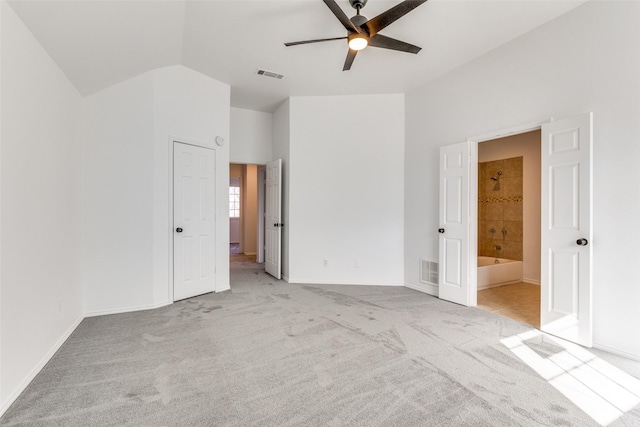 unfurnished bedroom with carpet floors, visible vents, ensuite bathroom, and lofted ceiling