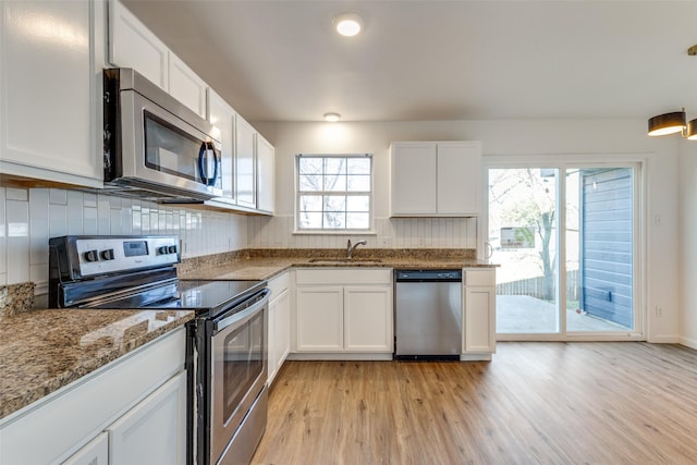 kitchen featuring appliances with stainless steel finishes, a sink, white cabinetry, and tasteful backsplash