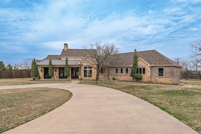 view of front of property with brick siding, fence, driveway, a front lawn, and a chimney