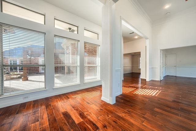 spare room with dark wood-style floors, visible vents, ornamental molding, and baseboards