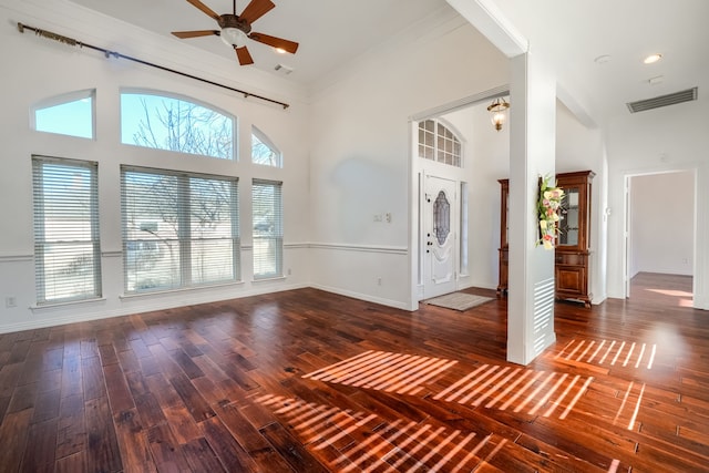 entryway featuring visible vents, baseboards, wood-type flooring, a high ceiling, and crown molding