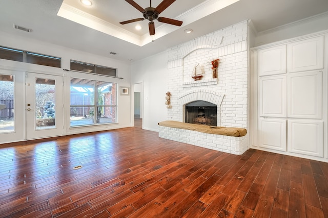 unfurnished living room featuring ornamental molding, dark wood-style flooring, a raised ceiling, and visible vents