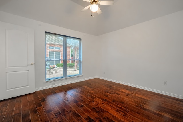 spare room with dark wood-type flooring, a ceiling fan, and baseboards