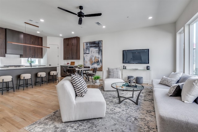 living area with light wood finished floors, a ceiling fan, visible vents, and recessed lighting