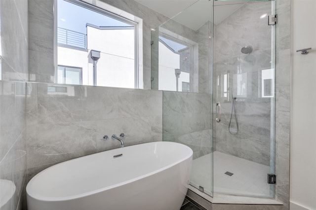 bathroom with a freestanding tub, a shower stall, and tile walls