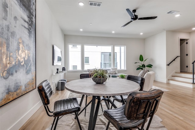 dining space featuring light wood-type flooring, visible vents, and stairs