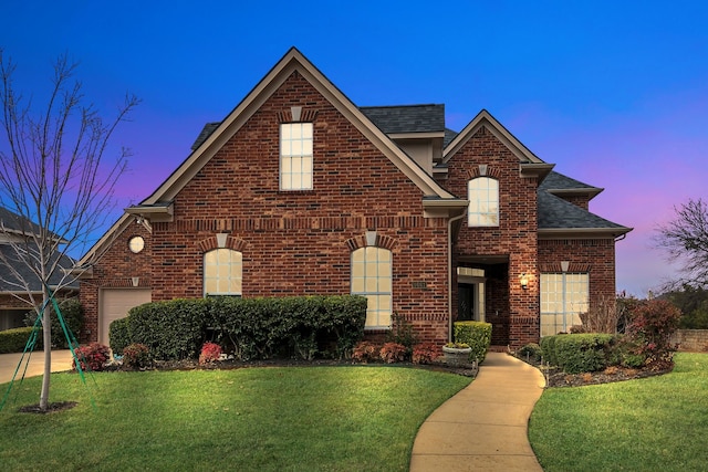traditional-style house with brick siding, a front lawn, and roof with shingles
