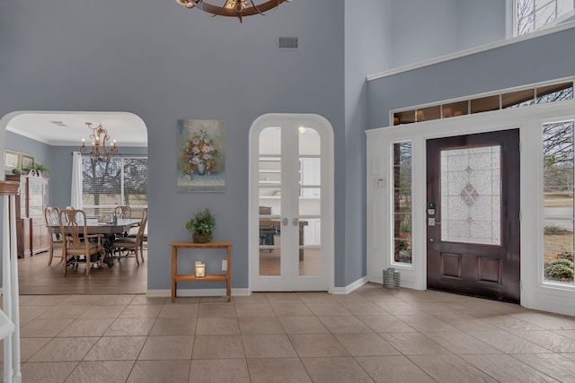entrance foyer with visible vents, plenty of natural light, an inviting chandelier, and light tile patterned floors