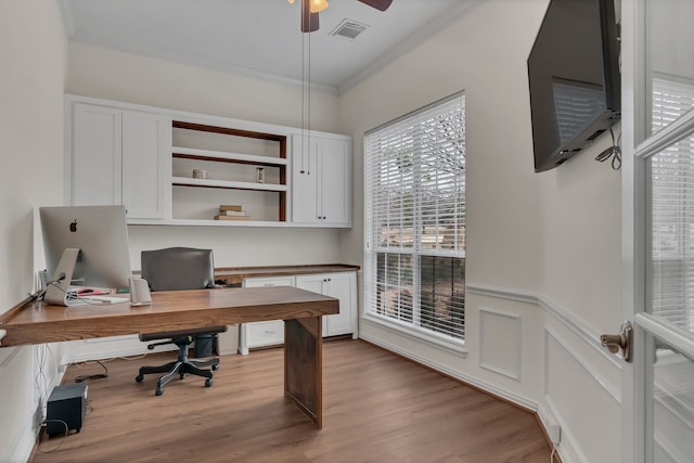 home office with ornamental molding, a ceiling fan, visible vents, wood finished floors, and wainscoting