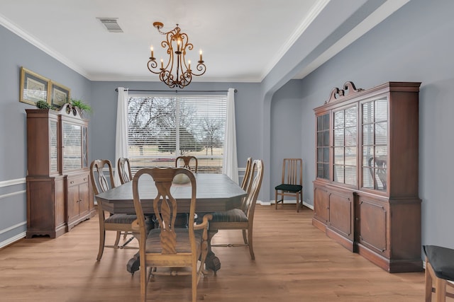 dining area with crown molding, an inviting chandelier, light wood-type flooring, visible vents, and baseboards
