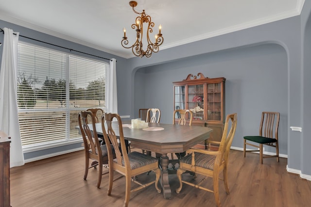 dining space with baseboards, arched walkways, an inviting chandelier, dark wood finished floors, and crown molding