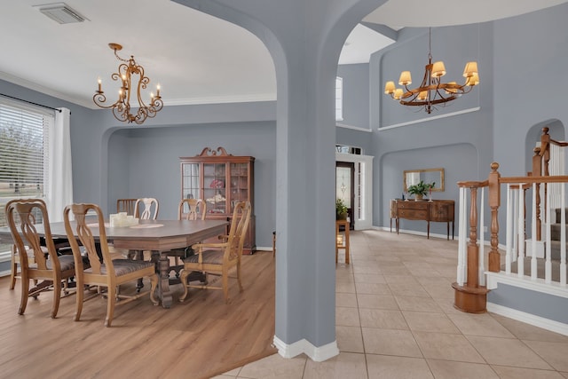 dining area featuring baseboards, a chandelier, light tile patterned floors, visible vents, and arched walkways
