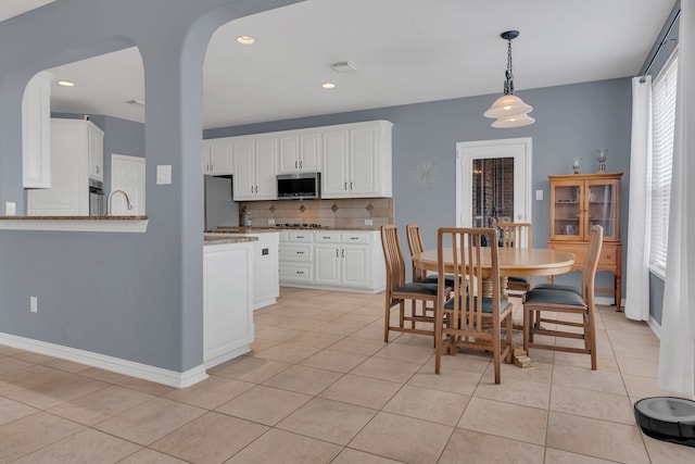 kitchen featuring visible vents, light tile patterned floors, white cabinetry, stainless steel appliances, and backsplash