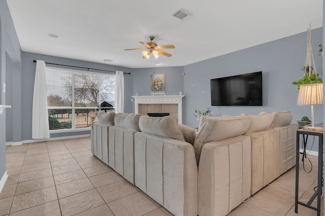 living room with visible vents, baseboards, a ceiling fan, and a fireplace