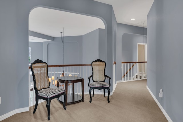 sitting room featuring attic access, baseboards, carpet, and an upstairs landing