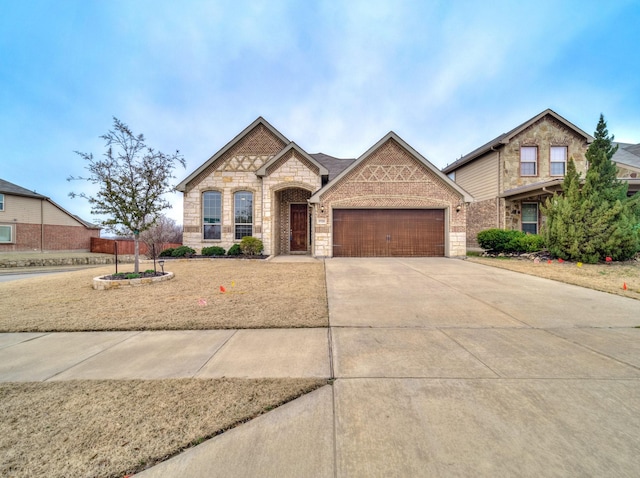 view of front facade with concrete driveway, an attached garage, brick siding, and stone siding