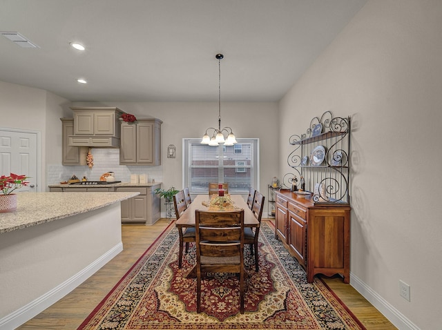 dining space with an inviting chandelier, light wood-style floors, visible vents, and baseboards