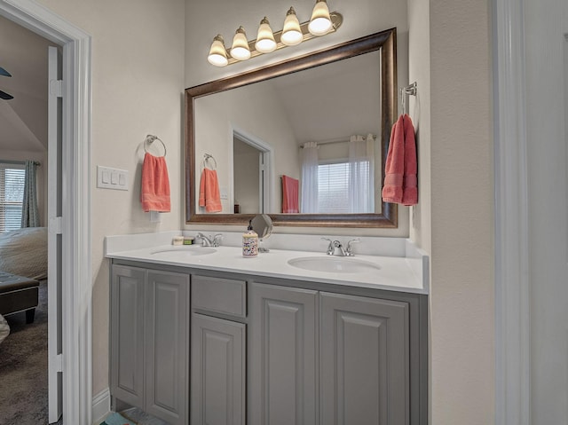 full bathroom with double vanity, connected bathroom, and a sink