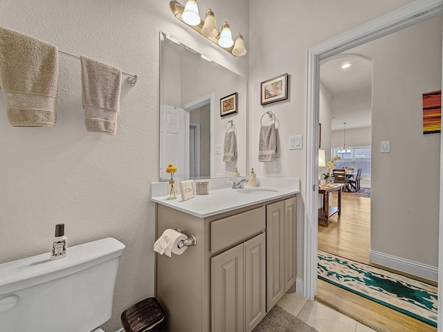 bathroom with vanity, toilet, wood finished floors, and baseboards