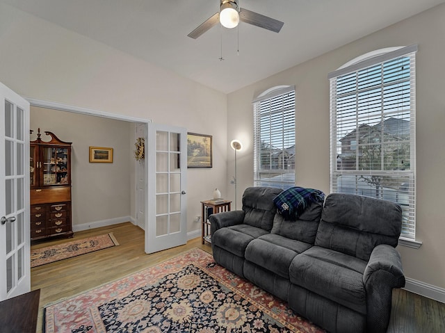 living area featuring french doors, a ceiling fan, light wood-type flooring, and baseboards