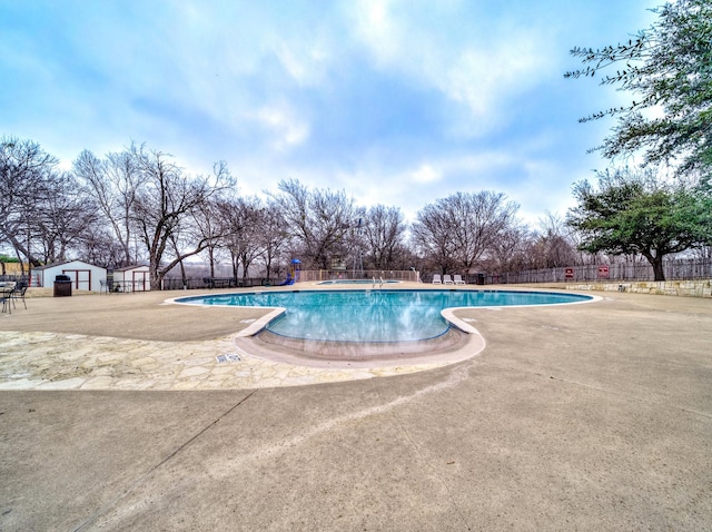 community pool featuring a patio, a jacuzzi, and fence