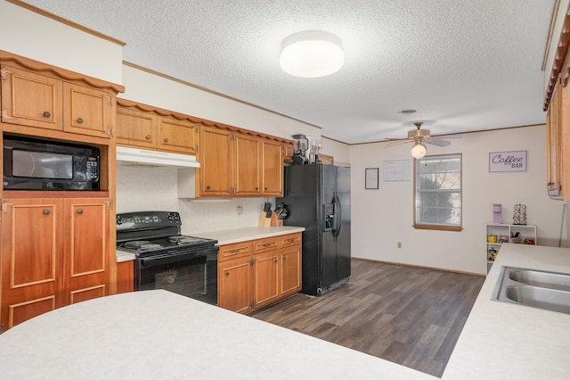 kitchen featuring black appliances, under cabinet range hood, light countertops, and dark wood-type flooring