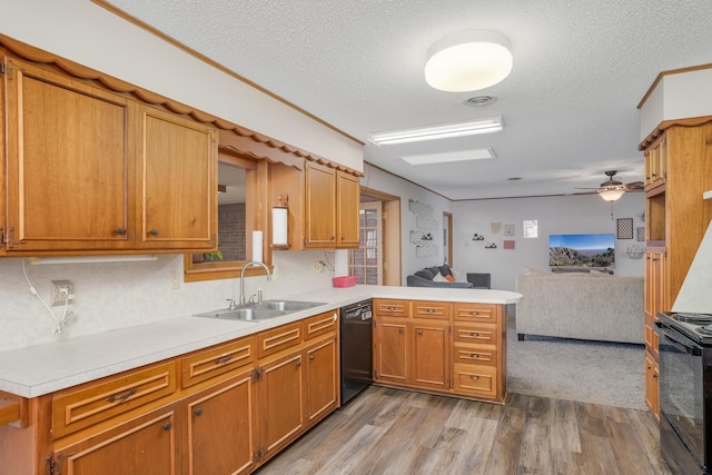 kitchen featuring light countertops, open floor plan, a sink, a peninsula, and black appliances