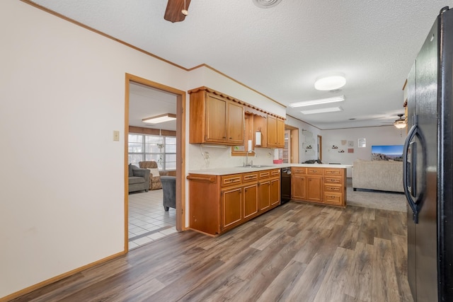 kitchen featuring light countertops, a ceiling fan, freestanding refrigerator, open floor plan, and a peninsula